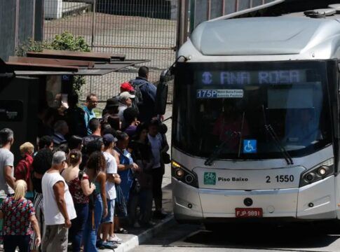 Fila de pessoas à espera do ônibus, ao lado