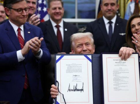 Trump exibe assinatura em projeto de lei, cercado de assessores e políticos no Salão Oval da Casa Branca