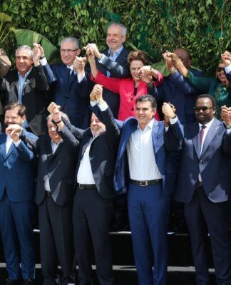 Delegados de vários países, com as mãos dadas e erguidas, posando para foto oficial da COP30