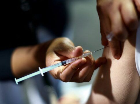 Close de uma seringa de vacinação aplicada no braço de uma pessoa