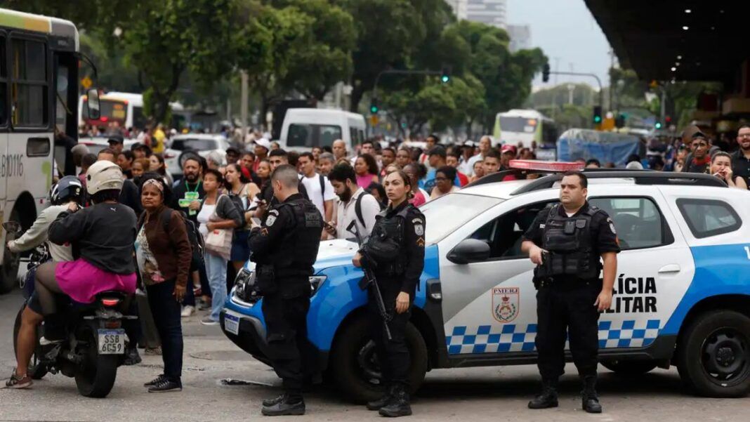 Policiais armados à frente de carros da própria polícia.