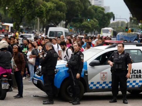 Policiais armados à frente de carros da própria polícia.
