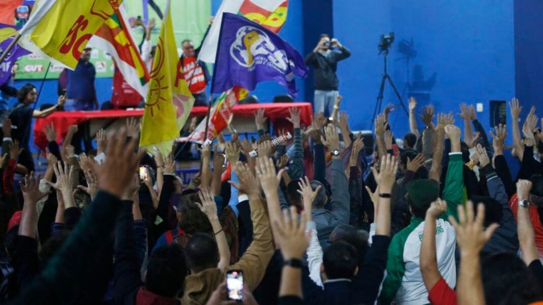 Multidão de sindicalizados em greve levantando as mãos