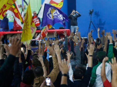 Multidão de sindicalizados em greve levantando as mãos