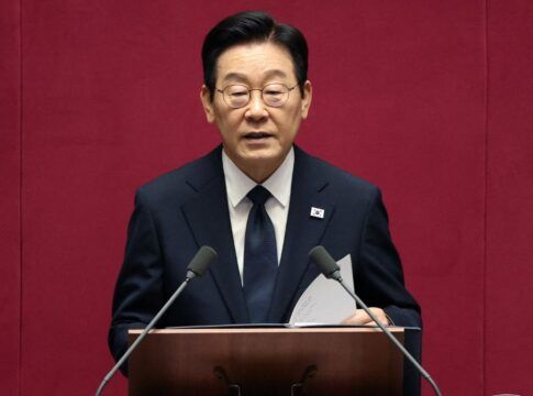 O presidente da Coreia do Sul fala ao microfone à frente de um fundo vermelho