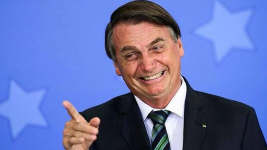 Foto antiga de Jair Bolsonaro, quando ainda era presidente, sorrindo e apontando com o dedo para fora da câmera