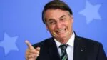 Foto antiga de Jair Bolsonaro, quando ainda era presidente, sorrindo e apontando com o dedo para fora da câmera