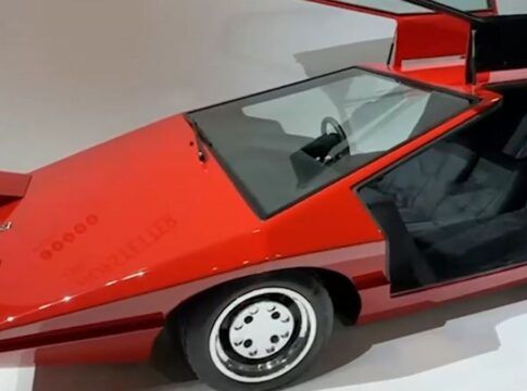 Foto de um carro esportivo vermelho de 1980, com bancos pretos e rodas de cor prateada