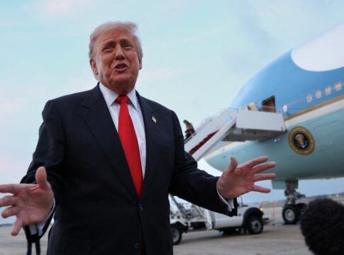 Donald Trump faz gesto com as mãos em frente a um avião