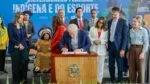 Lula assinando projeto de lei em palanque com ministros em volta