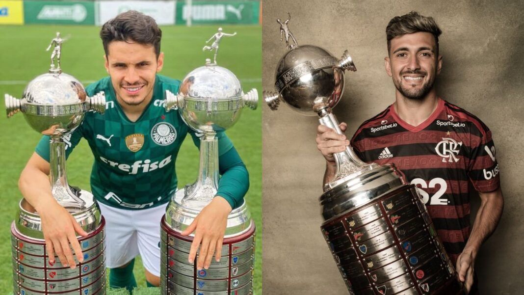 Em uma foto, Raphael Veiga, do Palmeiras, posa ao lado de duas taças da Libertadores, na outra, Arrascaeta, do Flamengo, segura o troféu da competição