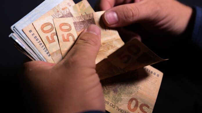 Notas de cinquenta reais sendo contadas.