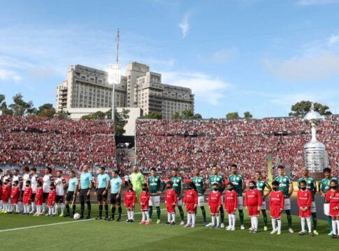 Os times de Palmeiras e Flamengo estão perfilados, com seus uniformes, para o hino nacional no gramado