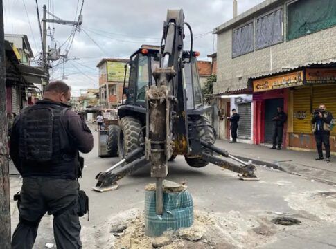 Trator desbloqueia rua enquanto policial observa