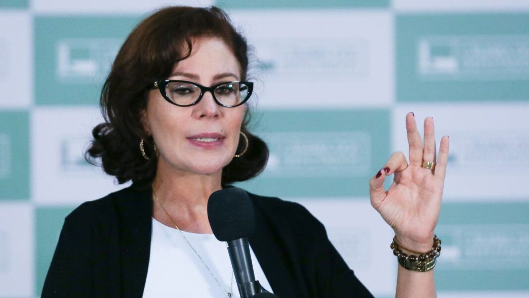 Carla Zambelli, na época em que era parlamentar, vestindo roupa formal e gesticulando com o sinal de 