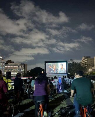Pessoas pedalando bicicletas enquanto assistem um filme em um telão