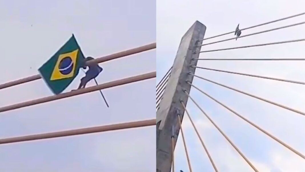 Imagem mostra um homem fincando uma bandeira do Brasil no alto de uma ponte estaiada, entre o Maranhão e Piauí