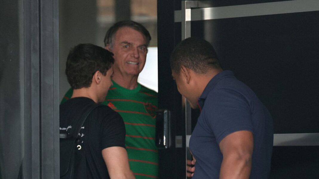 Imagem mostra o ex-presidente Jair Bolsonaro recebendo o deputado Nikolas Ferreira, que está de costas e com camisa preta. Ao lado, aparece um homem de camisa azul.