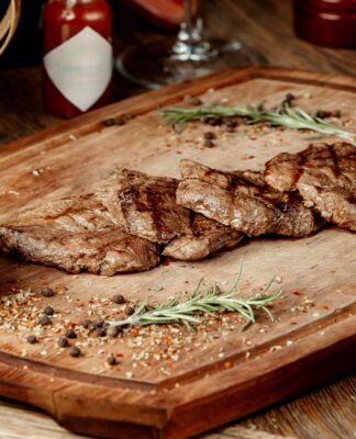 Imagem ilustrativa de carne frita em uma placa de madeira