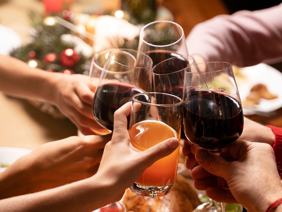 Na foto há pessoas brindando com vinho e suco.