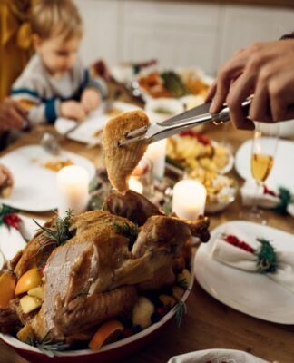 Close de a mão de um homem cortando um pedaço de frango na ceia de natal