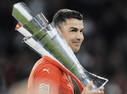 Cristiano Ronaldo, com a camisa de Portigal, segurando o troféu da Nations League sobre os ombros.