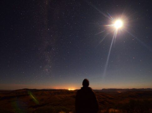 Em imagem ilustrativa, pessoa observa um eclipse se formando