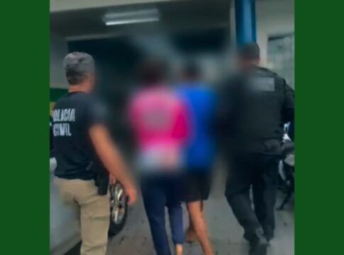 Imagem mostra a prisão de dois homens. Os rostos deles estão desfocados. Dois policiais os acompanham.