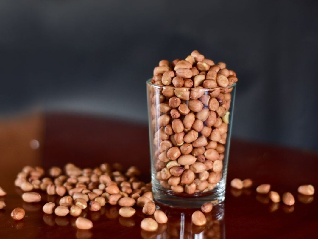 E imagem ilustrativa, há um copo estilo americano com feijões dentro e grãos caídos a mesa.