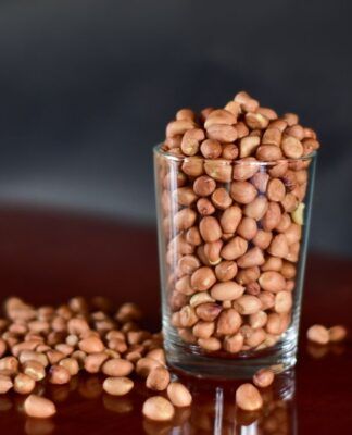 E imagem ilustrativa, há um copo estilo americano com feijões dentro e grãos caídos a mesa.