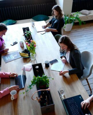 A imagem mostra um escritório com várias pessoas trabalhando numa mesa grande