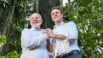 A imagem, com uma iluminação natural e suave, apresenta o Presidente do Brasil, Luiz Inácio Lula da Silva, e o Presidente da França, Emmanuel Macron, de pé, lado a lado, em um ambiente que parece ser uma floresta, possivelmente a Amazônia, como indicam os grandes troncos de árvores e a folhagem densa e escura no fundo.