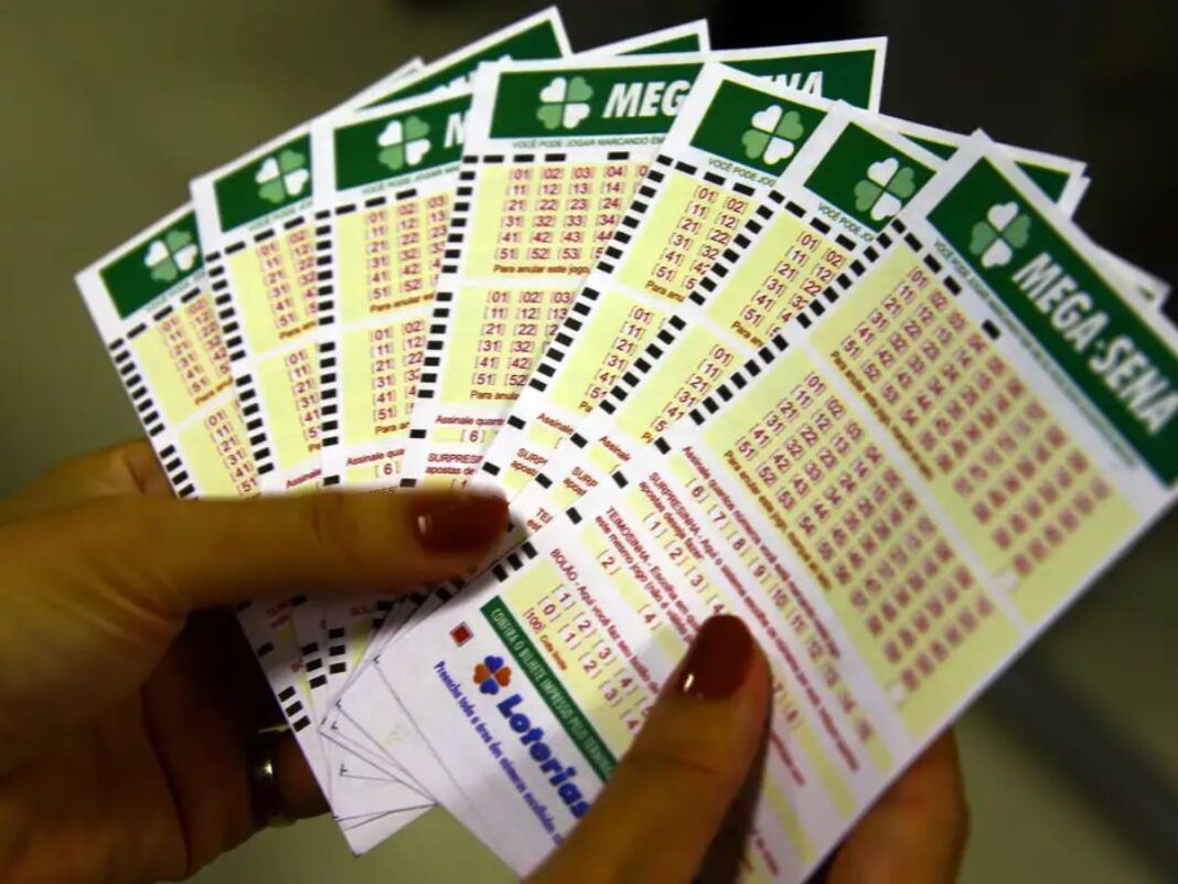 Pessoa segura em suas mãos cartões de apostas da Mega Sena