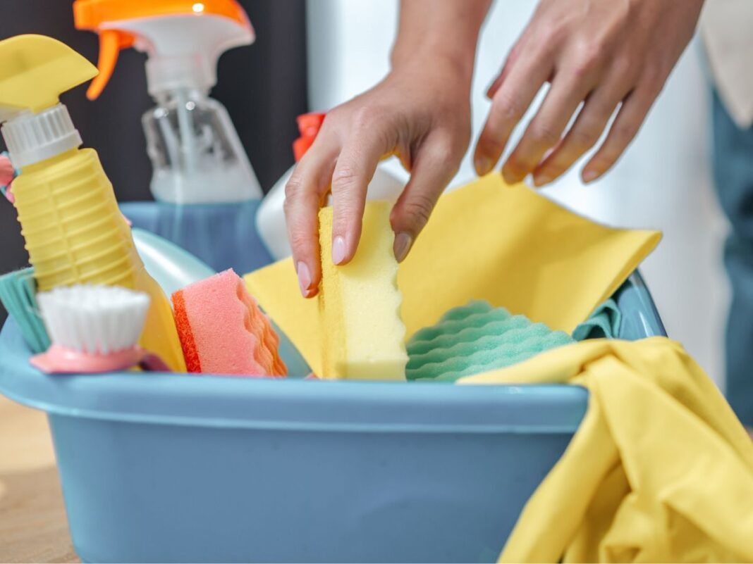 mãos de uma mulher pegando produtos de limpeza em uma caixa