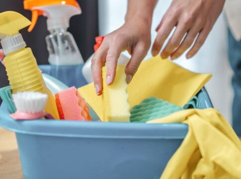 mãos de uma mulher pegando produtos de limpeza em uma caixa