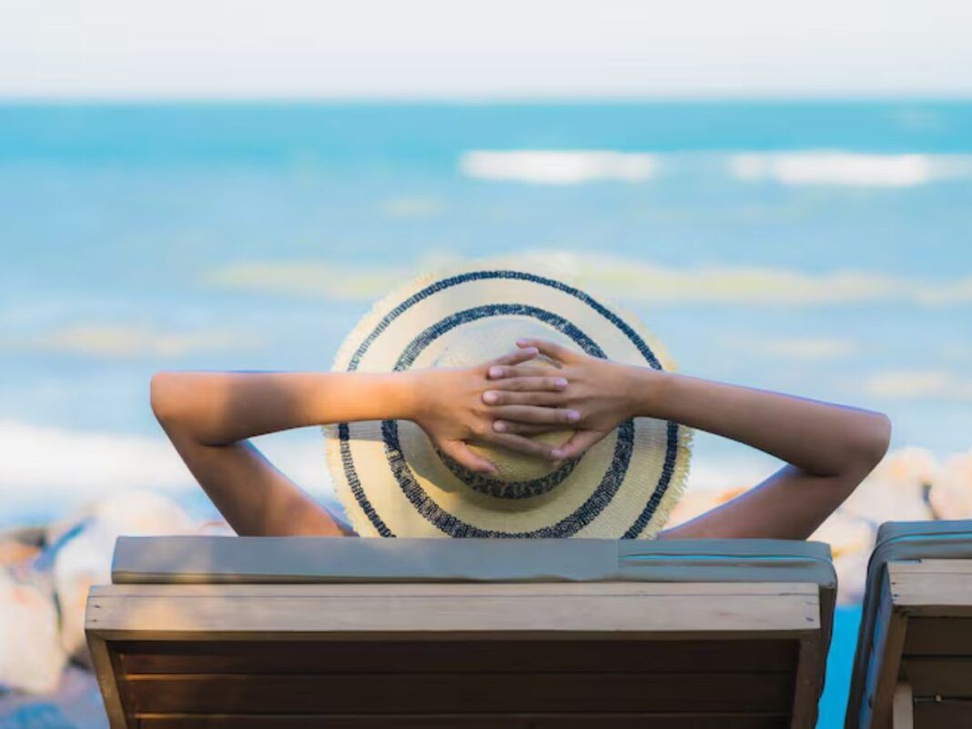 Homem na praia tomando um sol de chápeu