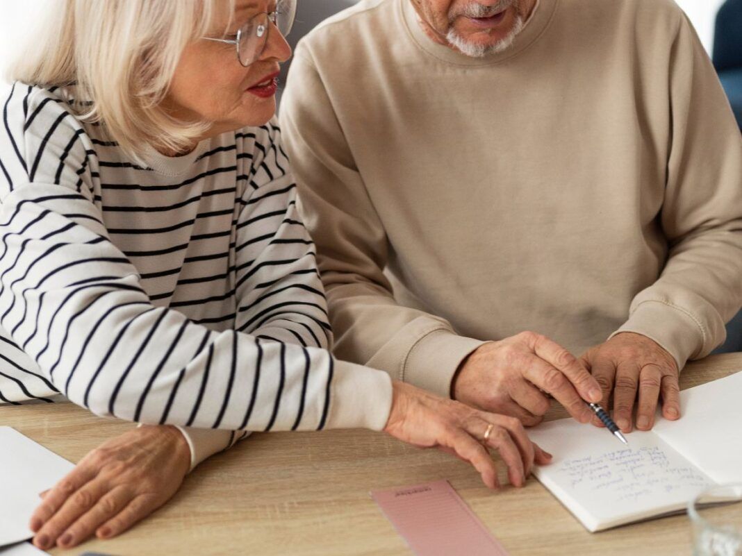 Em imagem ilustrativa, dois aposentados escrevendo em uma mesa