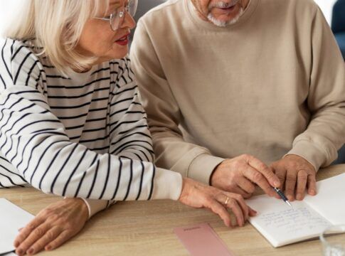 Em imagem ilustrativa, dois aposentados escrevendo em uma mesa