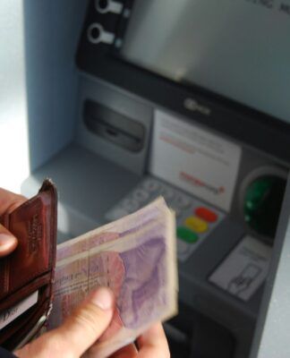 Em imagem ilustrativa, pessoa saca dinheiro em banco.