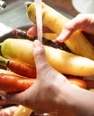 Em imagem ilustrativa, pessoa lava alimentos em água em abundância