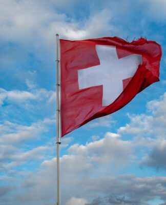 Imagem ilustrativa da bandeira da Suíça a céu aberto.
