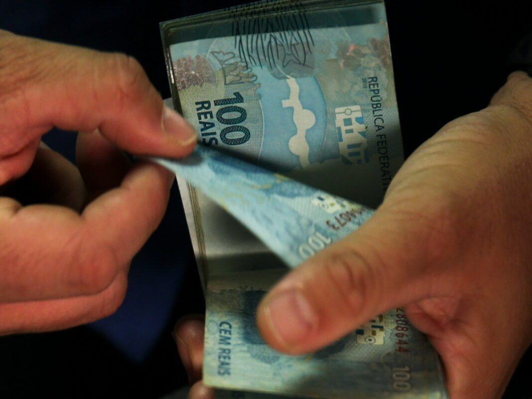 Imagem de dinheiro, notas de 100 reais nas mãos de um homem