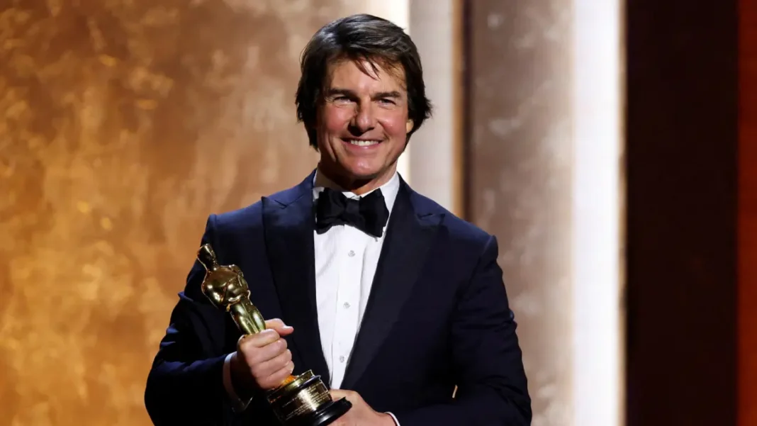 Ator Tom Cruise veste smoking e sorri com um Oscar honorário nas mãos, em evento especial da Academia