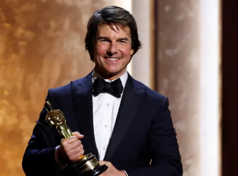 Ator Tom Cruise veste smoking e sorri com um Oscar honorário nas mãos, em evento especial da Academia