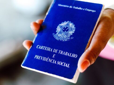 Em imagem ilustrativa, pessoa segura em suas mãos, uma carteira de trabalho brasileira.