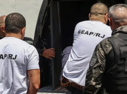 homens entrando em veículo policial para serem transferidos
