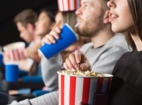 Em imagem ilustrativa, pessoas assistem ao cinema com pipoca