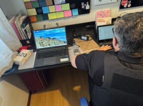 Policial acessa notebook numa escrivaninha na casa de um dos suspeitos