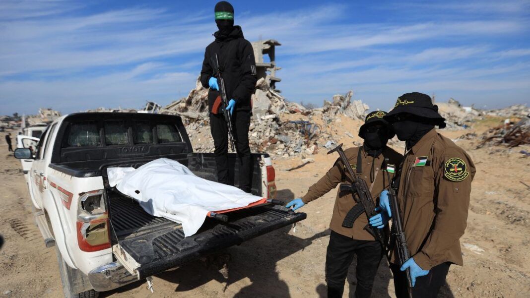 Militantes do Hamas e da Jihad Islâmica mostram corpo encoberto por lona branca sobre uma picape.