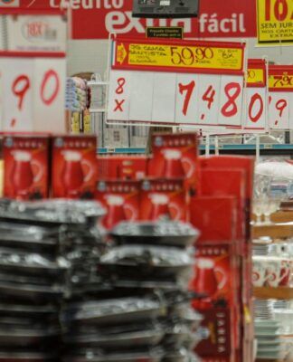 Imagem dentro de um mercado, mostrando várias placas de preços e alimentos nas prateleiras